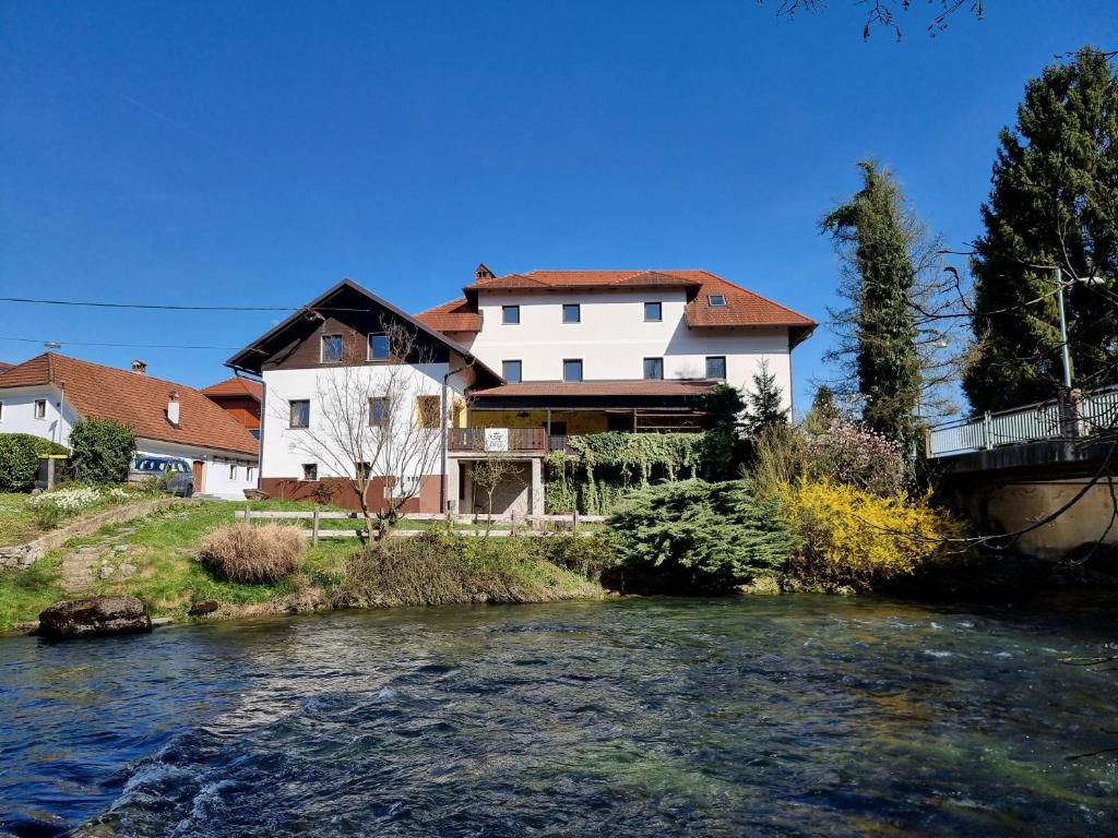 a house next to a river with a bridge at Krka River Lodge in Znojile pri Krki