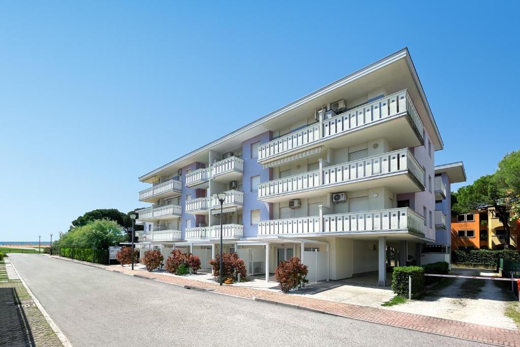 ein Apartmenthaus mit weißen Balkonen und einer Straße in der Unterkunft NEW Apartment Diana Ovest in Bibione