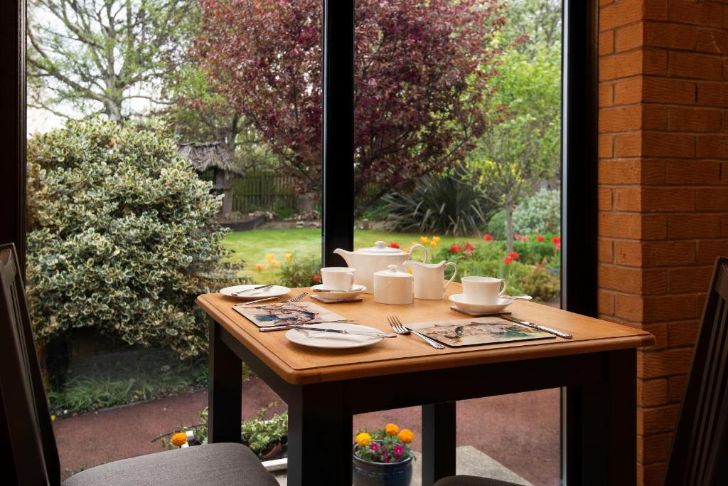 a table with cups and saucers on it in front of a window at Morwick House B&B in Warkworth