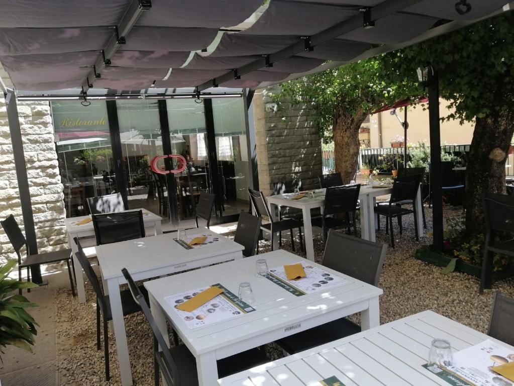 une terrasse avec des tables et des chaises blanches sous une tente dans l'établissement La Locanda di Bivigliano, à Bivigliano