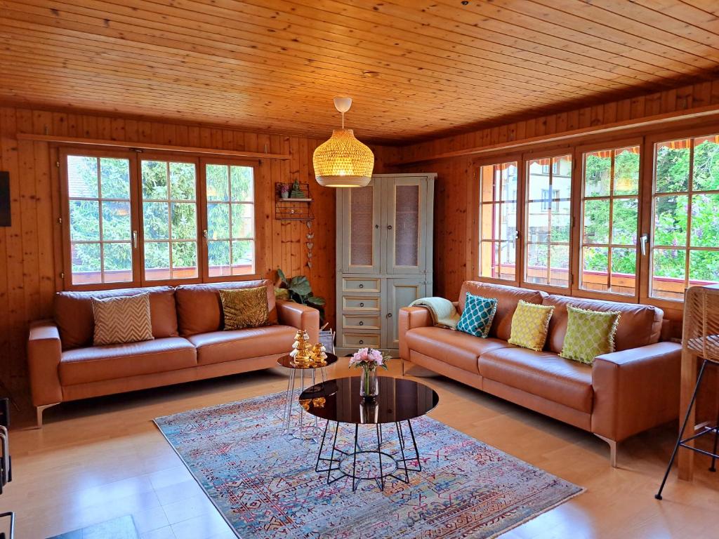 a living room with two couches and a table at Sawasdee Swiss Chalet Wilderswil in Wilderswil