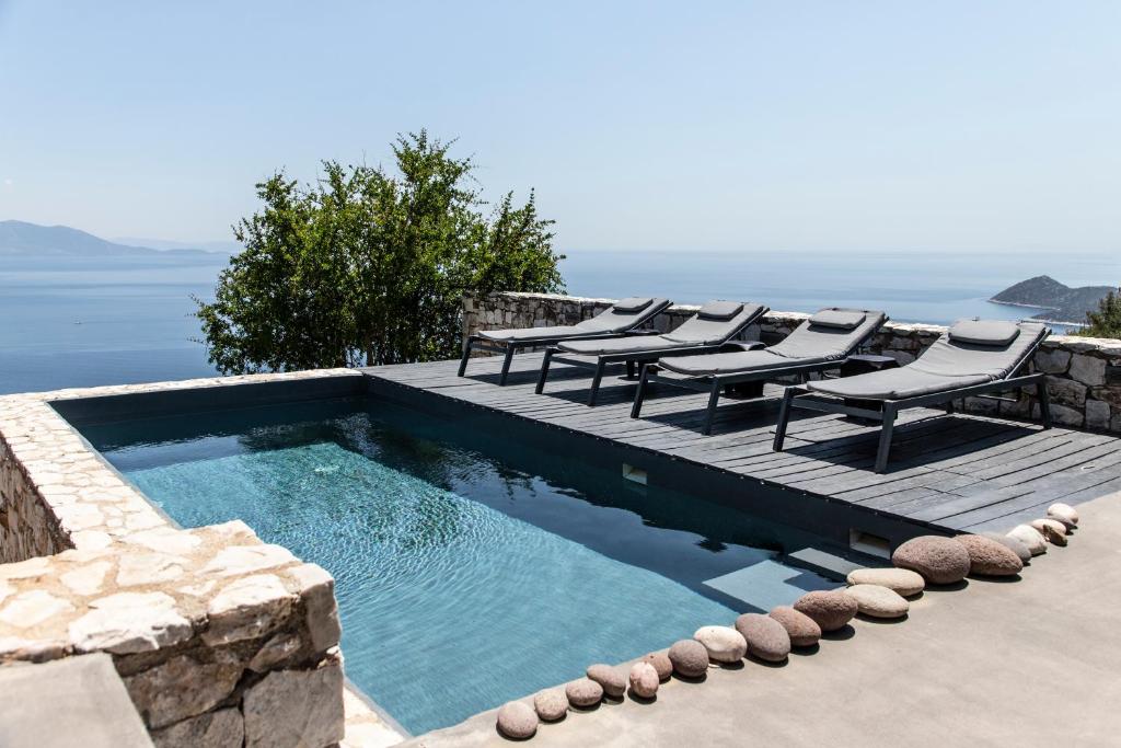 einen Pool mit Stühlen, Tischen und Meerblick in der Unterkunft Seaview Villa Schinias in Schinias