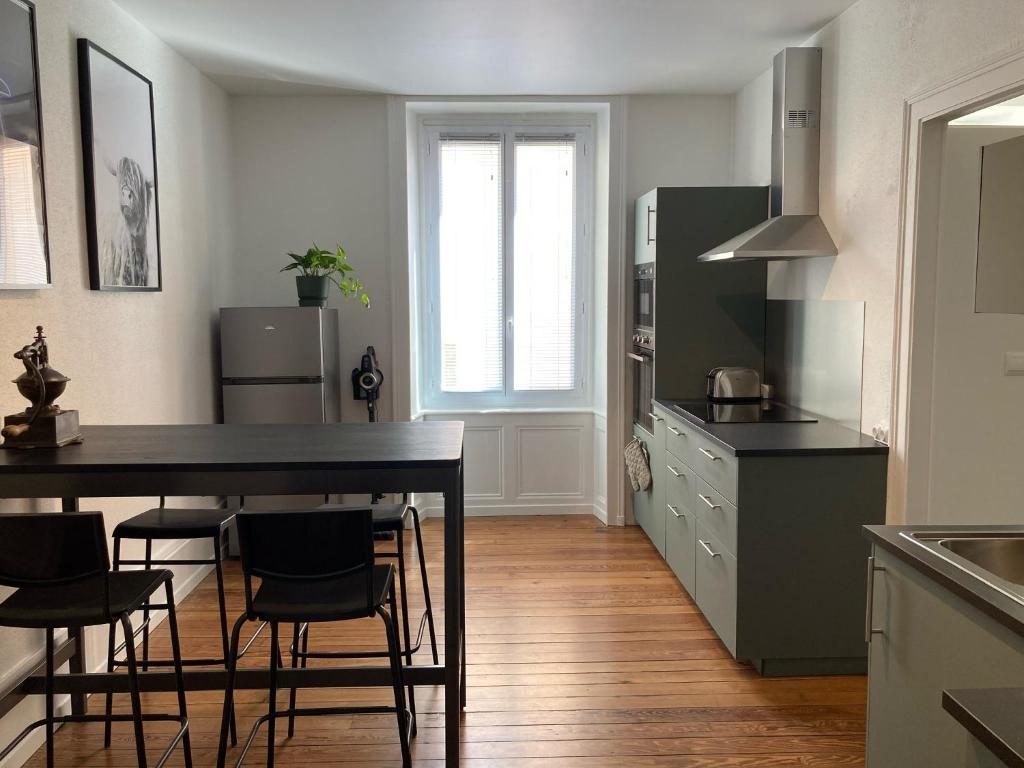 uma cozinha com mesa e cadeiras num quarto em Appartement avec place de parking et box vélos em Montbéliard