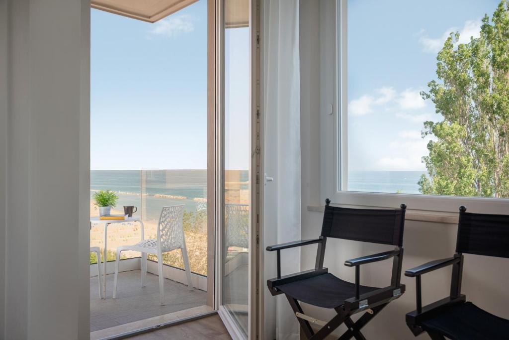 una camera con due sedie e un balcone con vista sull'oceano di Club Hotel a Gabicce Mare