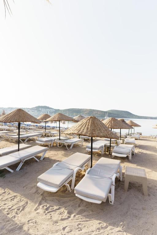 a group of lounge chairs and umbrellas on a beach at Costa Bitezhan Hotel - All Inclusive in Bitez