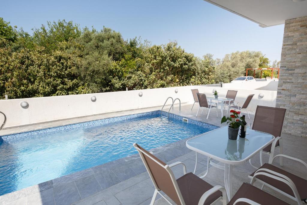 a patio with a table and chairs next to a swimming pool at Cosy Paphos Villa - By IMH Travel & Tours in Paphos City