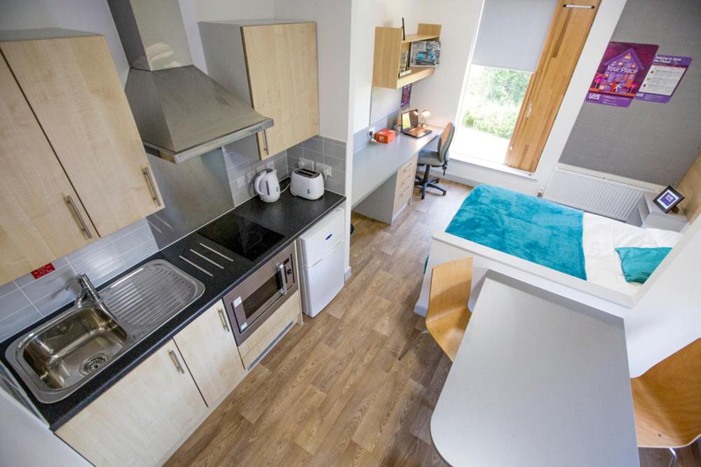 uma pequena cozinha com um lavatório e um fogão em Fferm Penglais Apartments em Aberystwyth