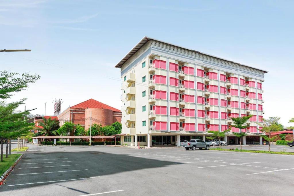 a large building with pink windows in a parking lot at V Resotel in Nonthaburi