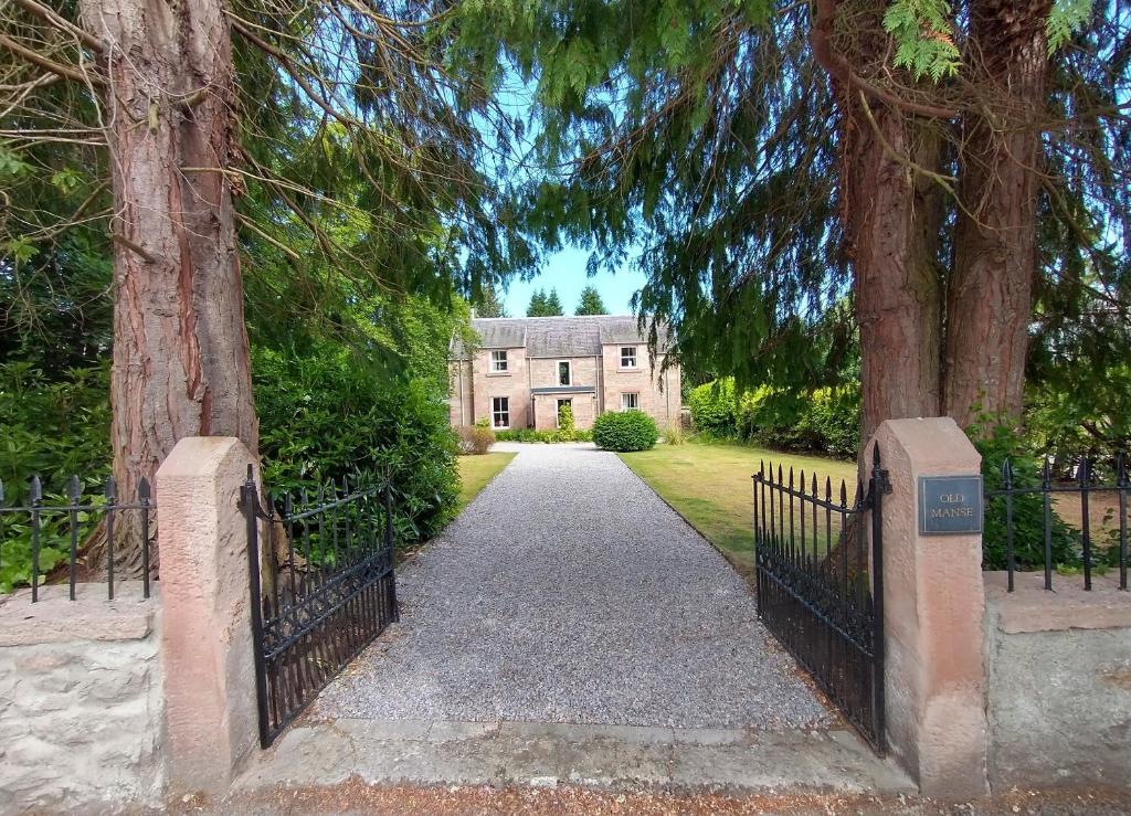 um portão que leva a uma casa com árvores em Old Manse em Muir of Ord