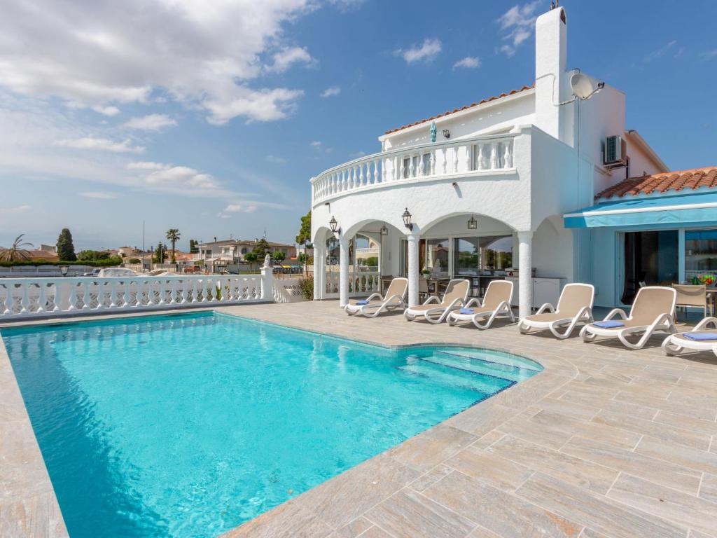 a villa with a swimming pool and chairs at Holiday Home Peni by Interhome in Empuriabrava