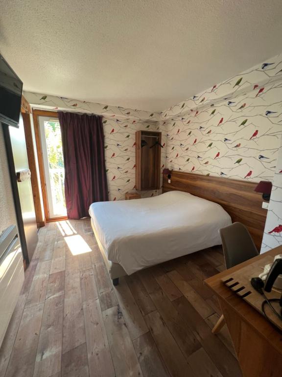 a bedroom with a large white bed and a desk at Cit'Hotel Le Montreal in Châlons-en-Champagne