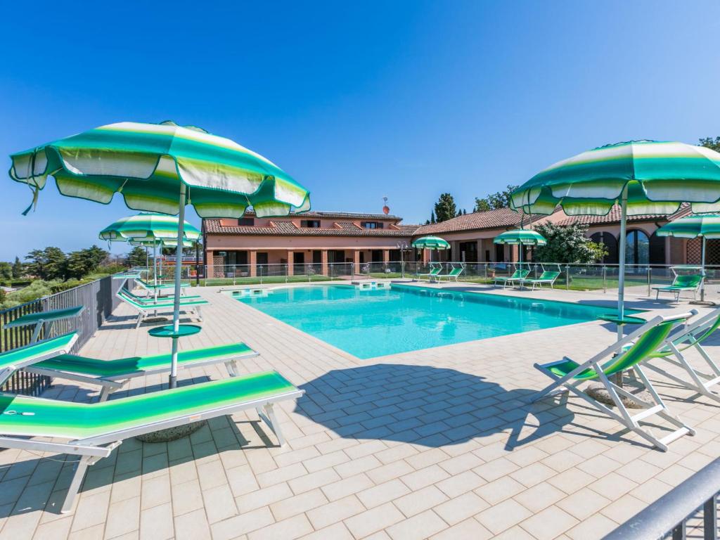 una piscina con sillas y sombrillas en Holiday Home Il Corbezzolo-2 by Interhome, en San Vincenzo