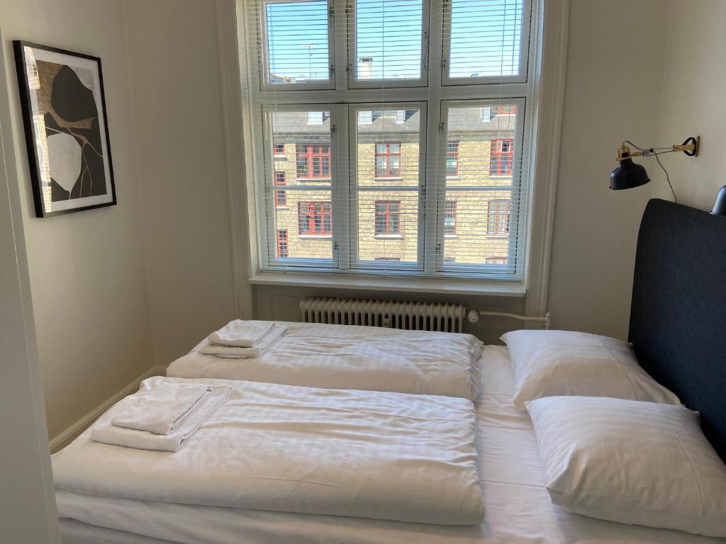 um quarto com 2 camas em frente a uma janela em Modern 1-bedroom apartment in charming Østerbro em Copenhague