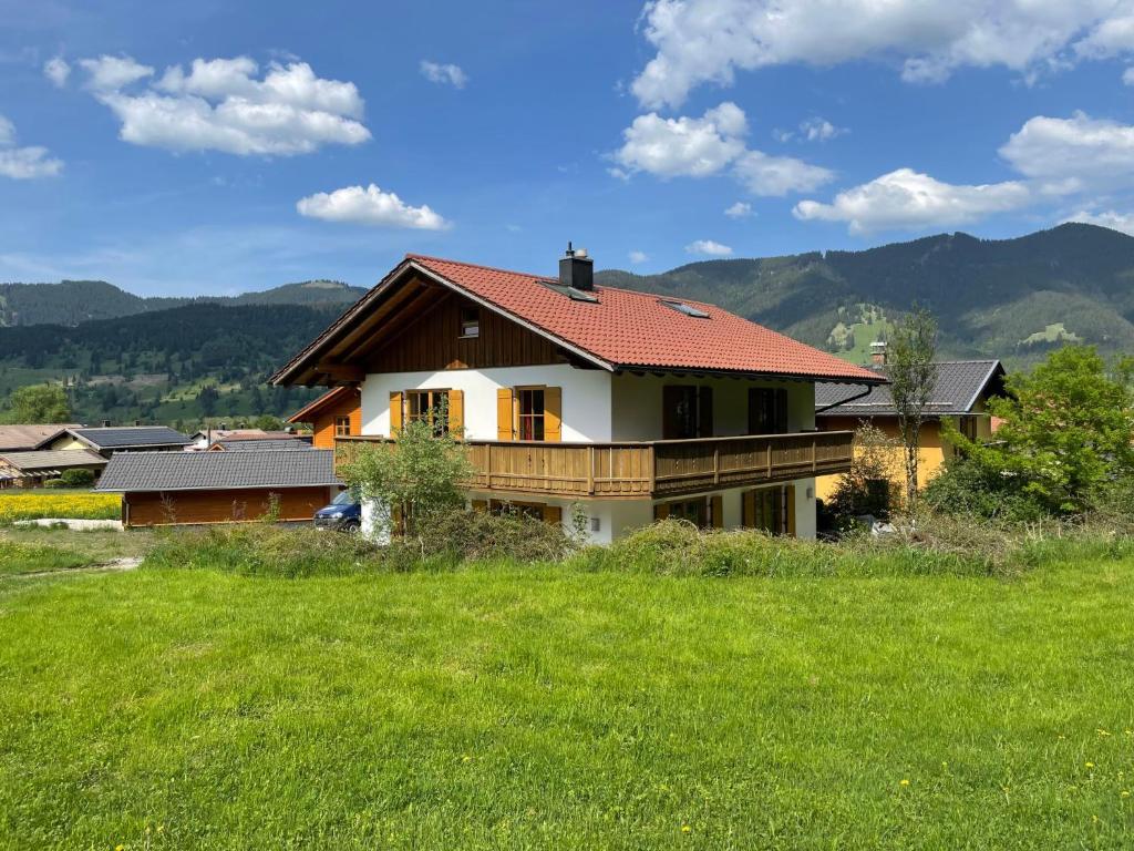 ein Haus mit rotem Dach auf einem grünen Feld in der Unterkunft Holiday Home Schwänli by Interhome in Oberammergau