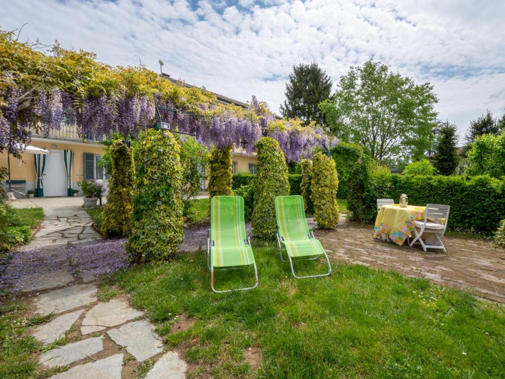 einen Garten mit zwei Stühlen, einem Tisch und lila Blumen in der Unterkunft Holiday Home Casa Margherita by Interhome in Asti