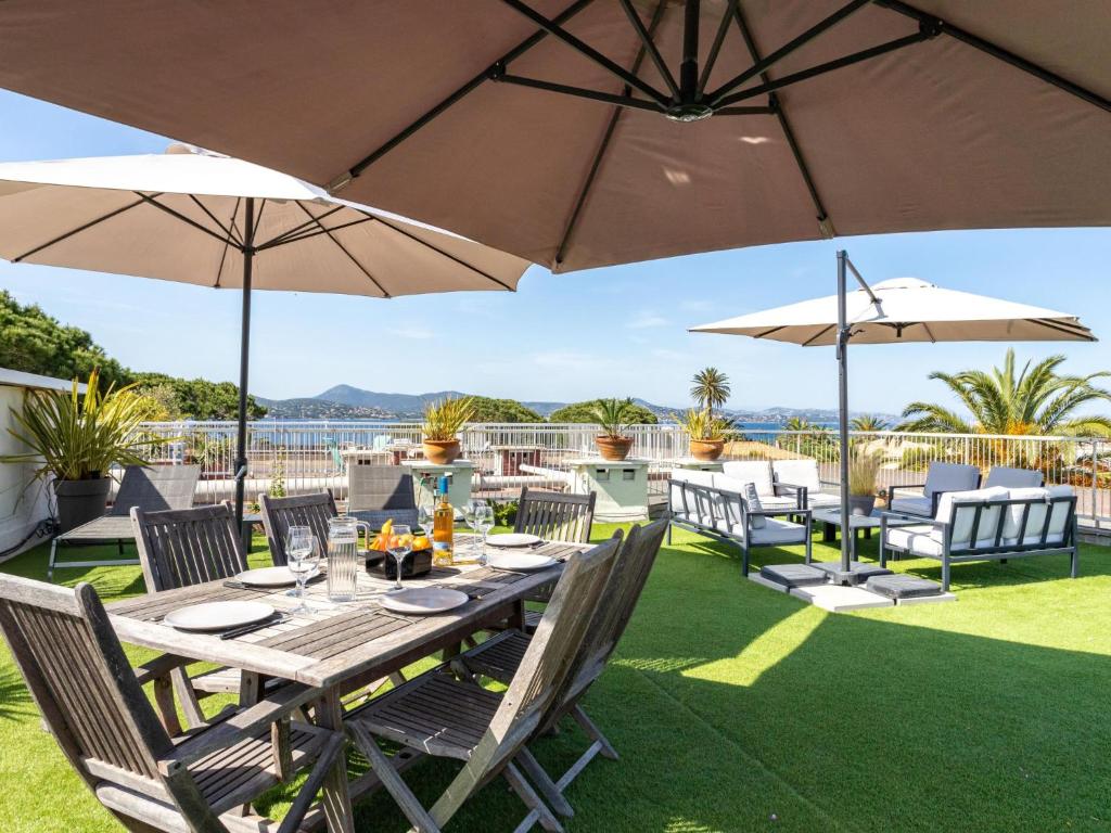 une table et des chaises avec des parasols sur une pelouse dans l'établissement Apartment Les Patios-7 by Interhome, à Saint-Tropez