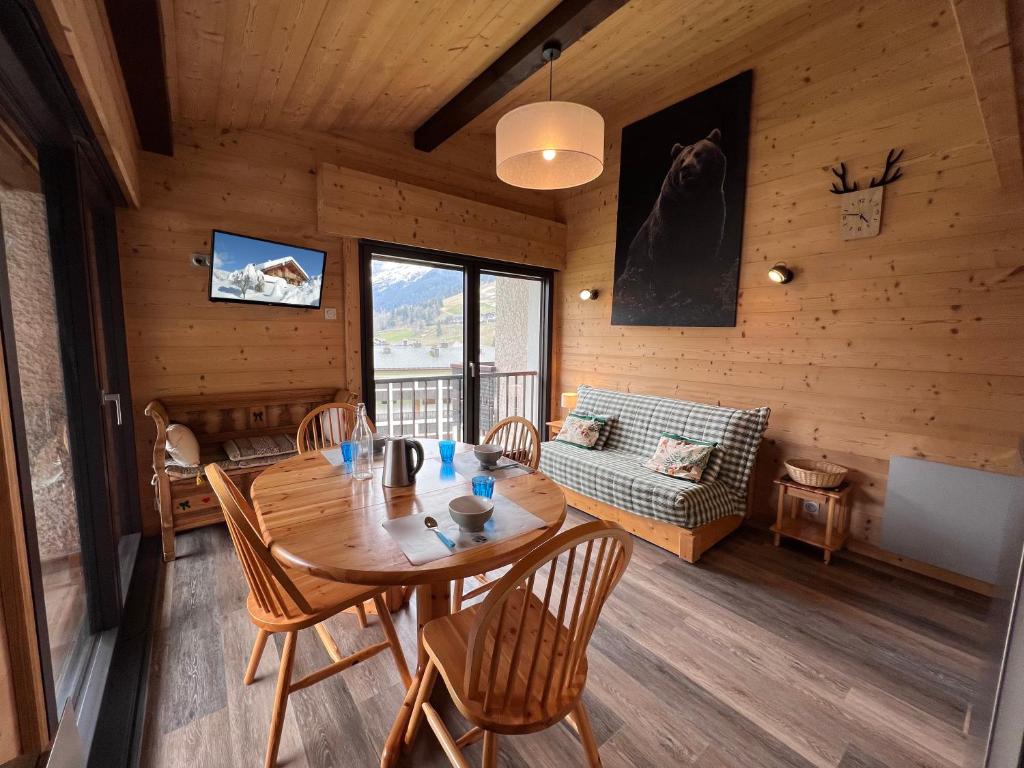 une salle à manger avec une table et des chaises dans une cabine dans l'établissement Sapaudia G - Appartement skis aux pieds, belle vue, à La Clusaz