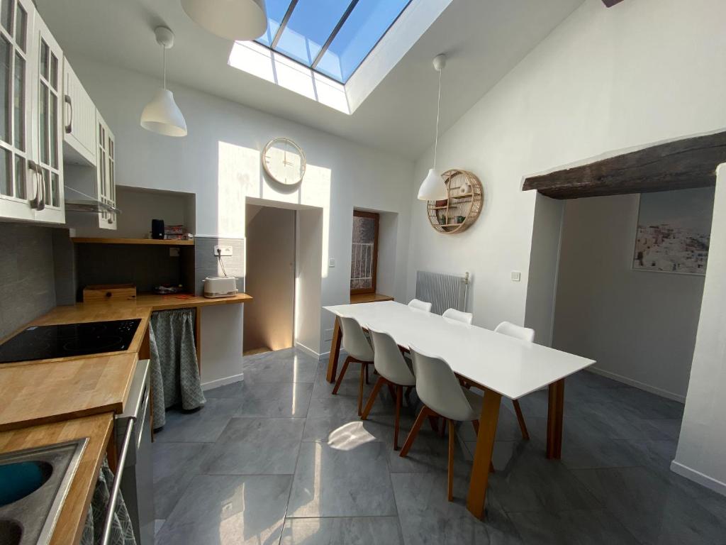 una cucina con un lungo tavolo bianco e sedie di La Mansarde De L Abbaye a Cluny