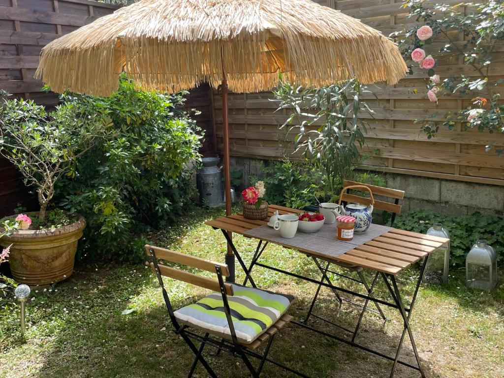 una mesa y sillas bajo una sombrilla de paja en Wisteria, en Eysines