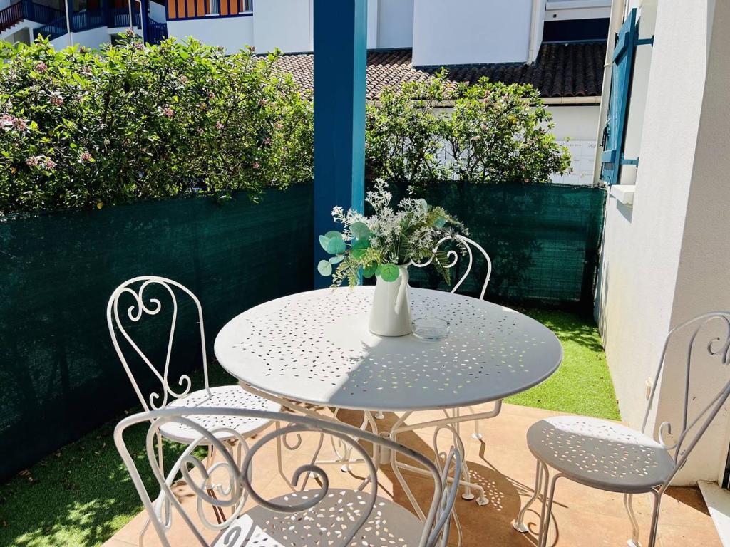 una mesa y sillas con un jarrón de flores. en Appartement Cambo-les-Bains, 1 pièce, 2 personnes - FR-1-495-105, en Cambo-les-Bains
