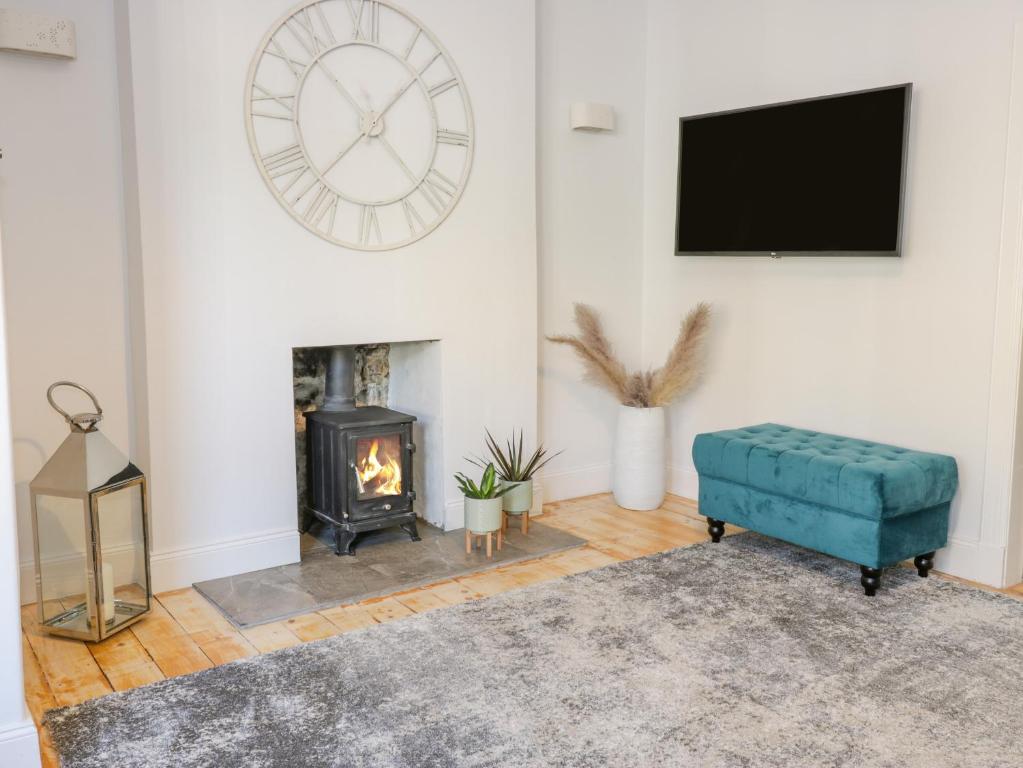 a living room with a fireplace and a clock on the wall at The Lazy Seal in Berwick-Upon-Tweed