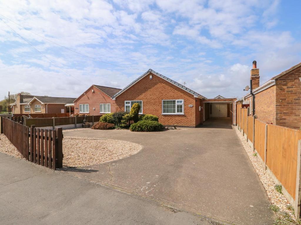 a brick house with a fence and a driveway at Sea Point in Skegness