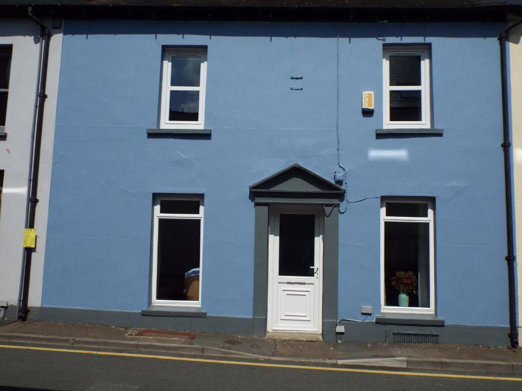 a blue building with a white door on a street at Cosy Cottage In Cardigan in Cardigan