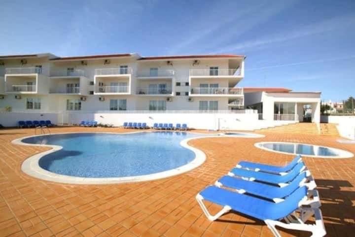 a resort with a swimming pool and two lounge chairs at T1 Apartment Cabanas in Cabanas de Tavira