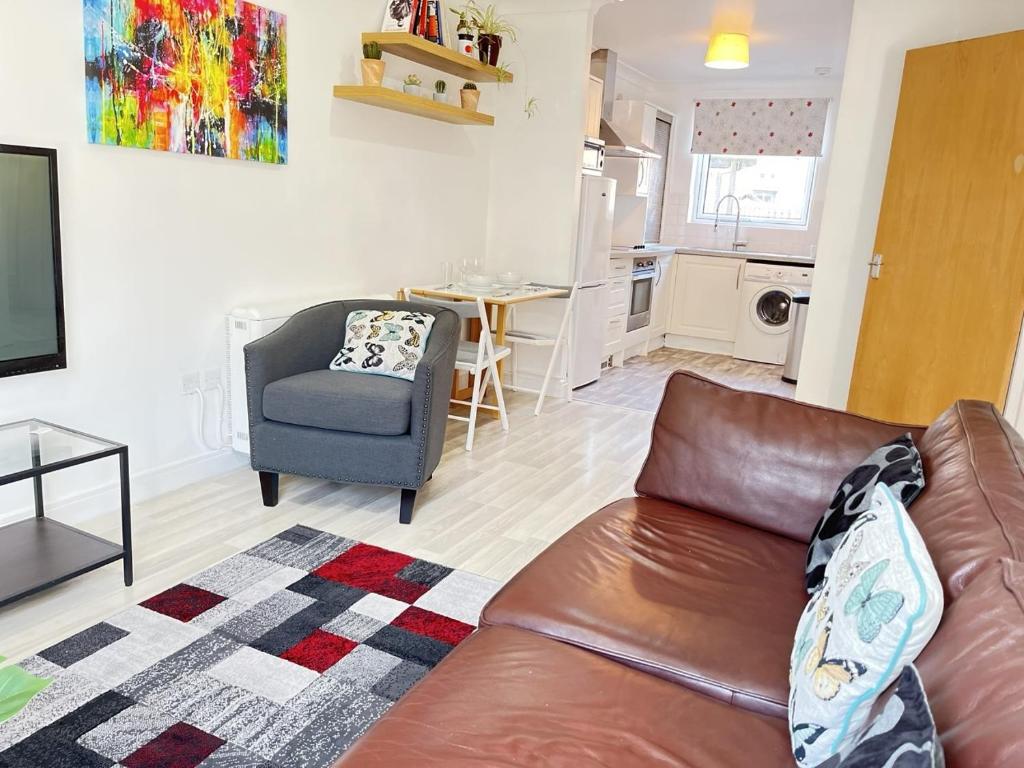 un soggiorno con divano in pelle marrone e una cucina di Bright 2 Bedroom Apartment - Edinburgh a Edimburgo