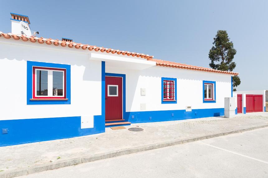 a white and blue house with a red door at Casa do Peladiço in Fataca