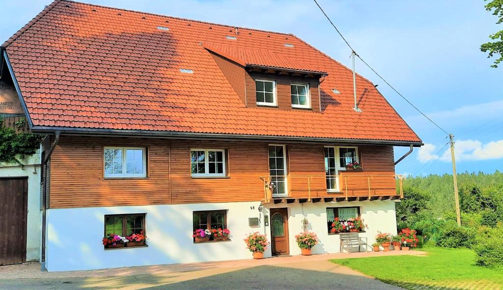 una casa con techo naranja y flores en las ventanas en Ferienwohnung Süßes Häusle, en Breitnau