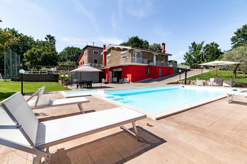 einen Pool mit zwei Liegestühlen und ein Haus in der Unterkunft Villa Vacanze La Quercia in Carbognano