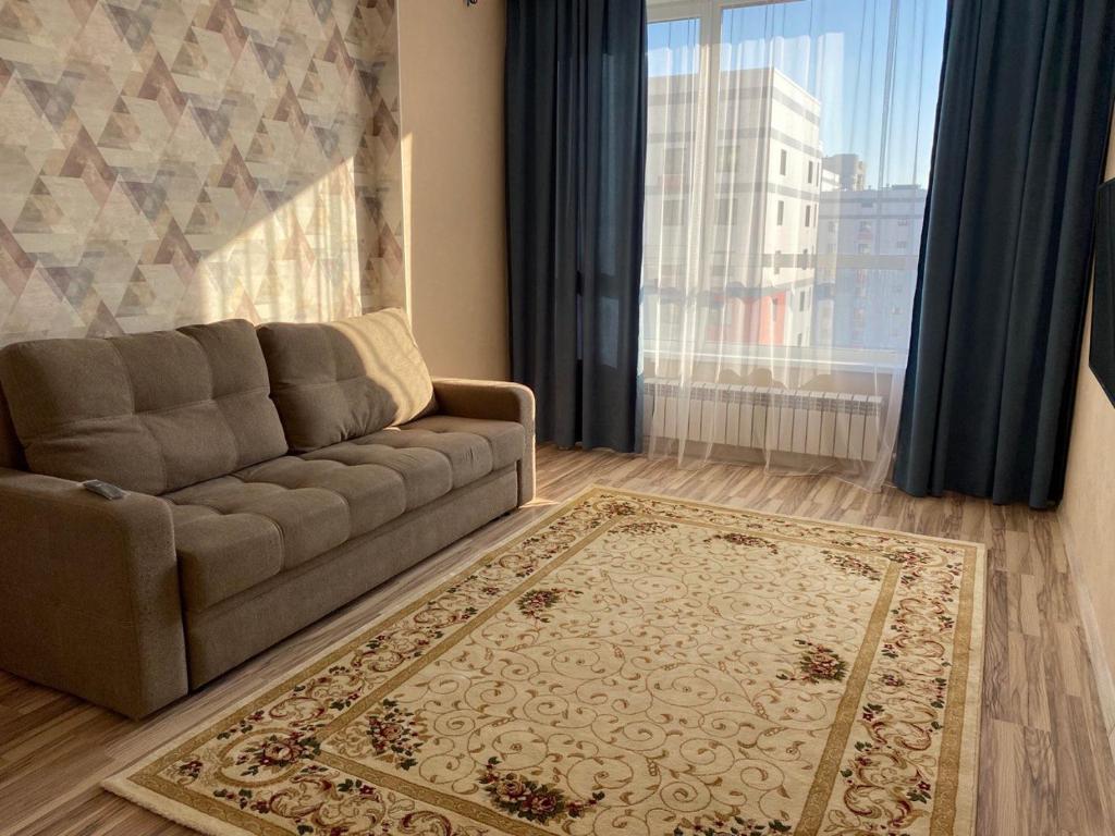 ein Wohnzimmer mit einem Sofa und einem großen Fenster in der Unterkunft ЖК Sat City блок С in Astana