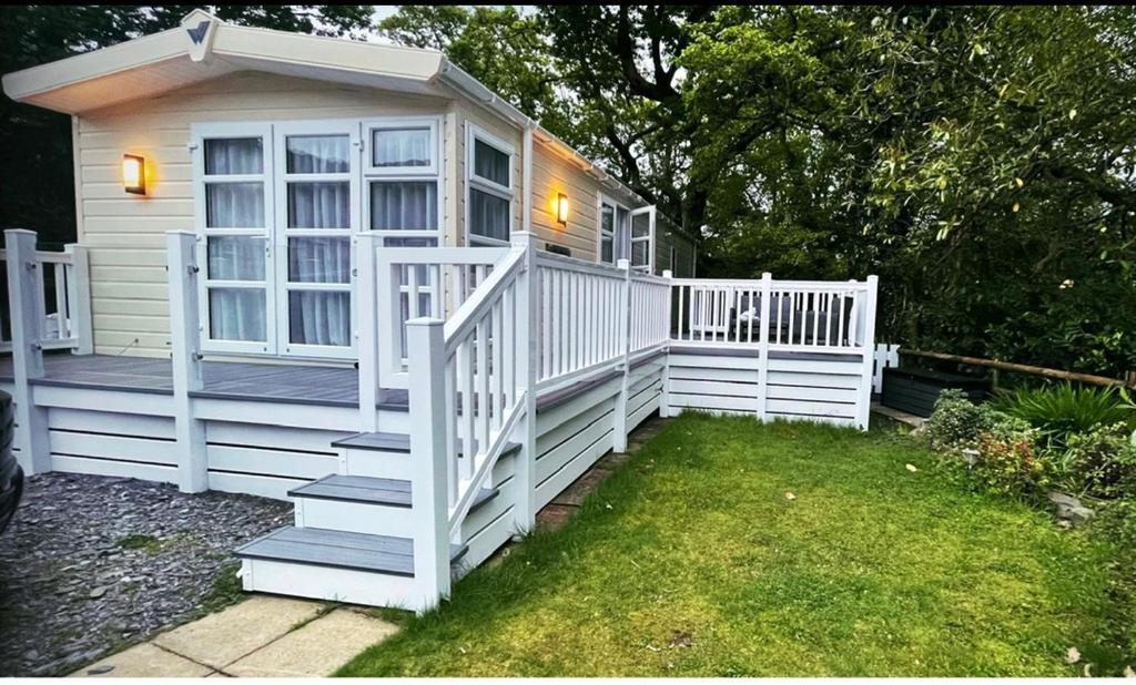 a small white house with a white fence and stairs at Snowdonia Holidays Caravan Hire - Aberdunant Park - 34 The Green in Prenteg