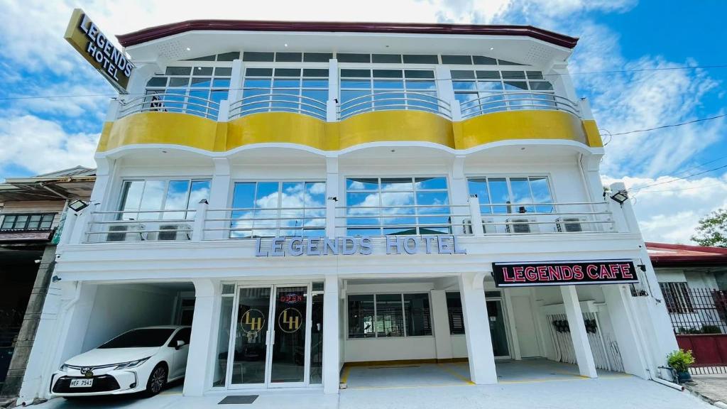 un edificio bianco e giallo con un'auto parcheggiata di fronte di Legends Hotel & Events Hall - Lemery & Taal a Lemery