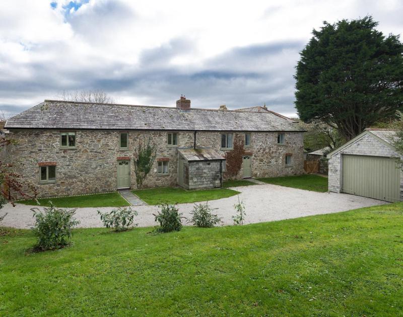 an old stone house with a garage in a yard at Orchard Cottage in Saint Endellion