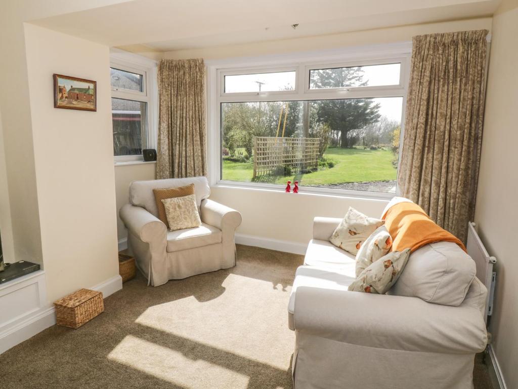 a living room with a couch and a chair and a window at 7 Cummertrees in Annan