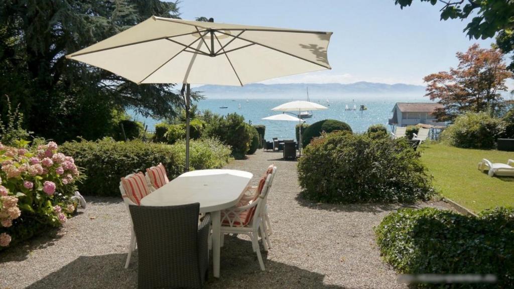 a table and chairs with an umbrella and the ocean at Villa Gerster in Wasserburg am Bodensee