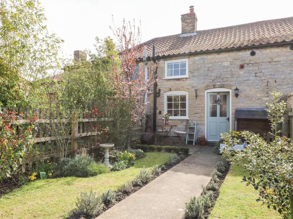 an old stone house with a garden in front of it at The Cottage in Lincoln