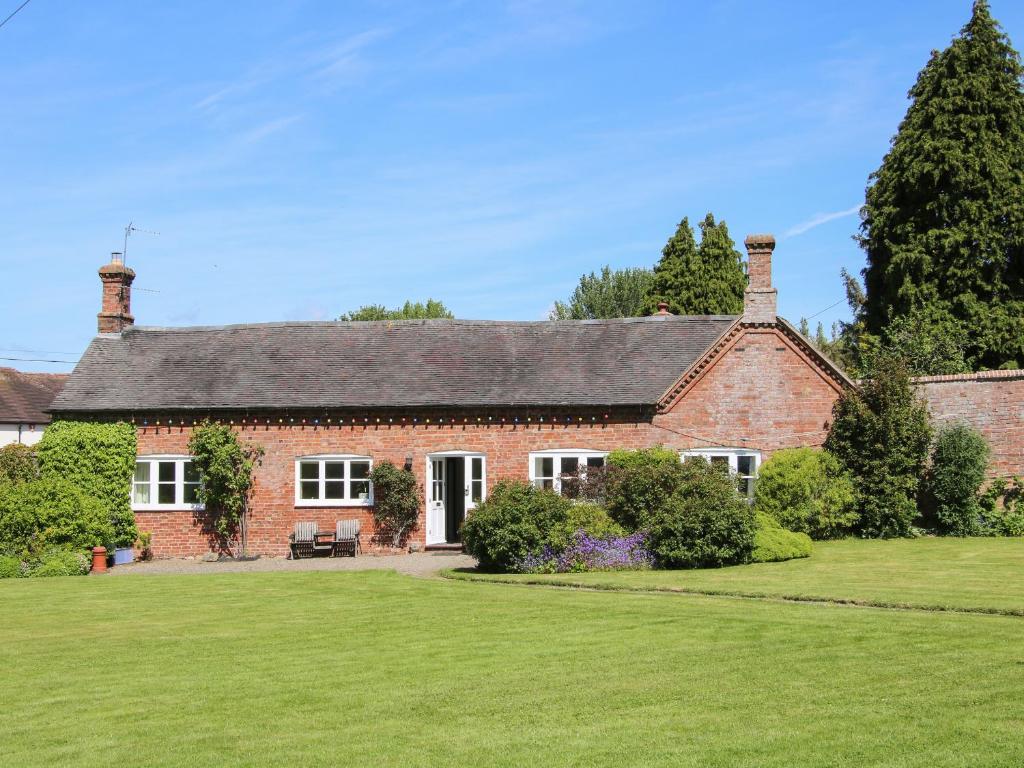 una casa de ladrillo rojo con un gran patio en The Stables en Shrewsbury