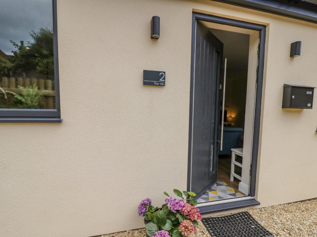 a door to a house with flowers on the side at 2 The Villa in Ludlow