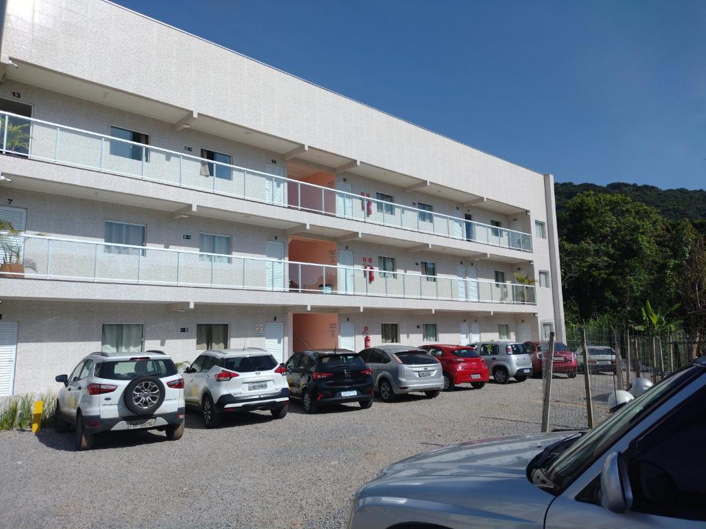 a parking lot with cars parked in front of a building at Apartamentos Margarida in Ubatuba