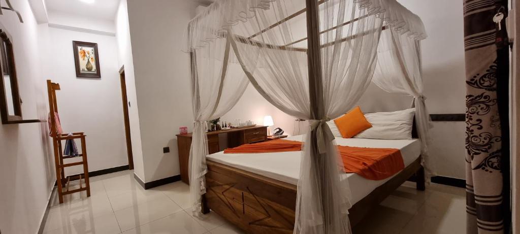 a bedroom with a canopy bed with orange pillows at Maduranga n Guest in Mirissa