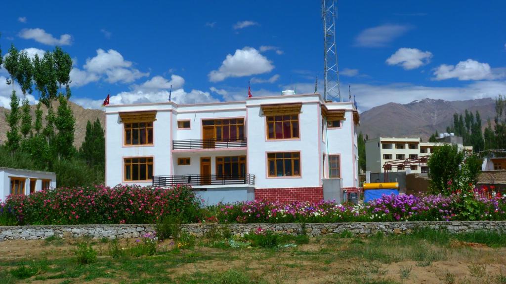 a white house with flowers in front of it at Orion Home in Leh