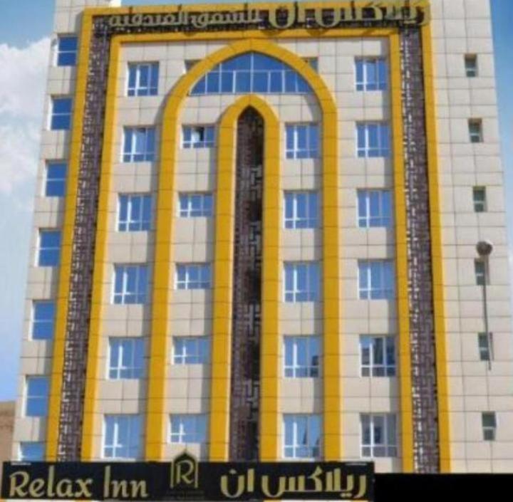 a tall building with a sign in front of it at ريلاكس ان للشقق الفندقية relax inn in Muscat