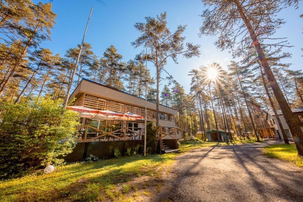 a house in the woods with the sun in the background at Villa Marika Holiday Centre in Alajõe