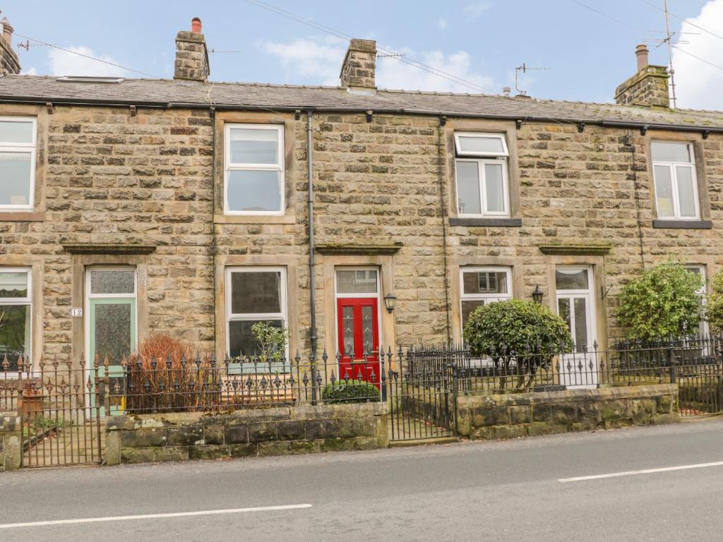 a brick house with a red door on a street at Crag View Cottage in Skipton