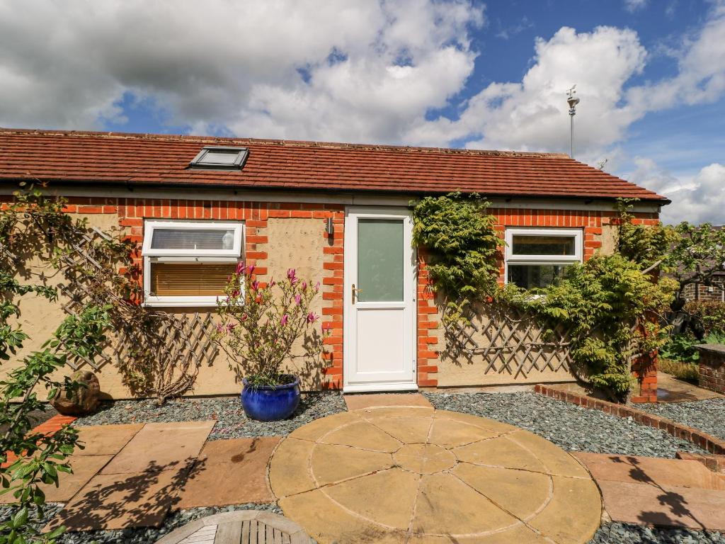 a brick house with a white door and a patio at Garden Cottage in Ilkley