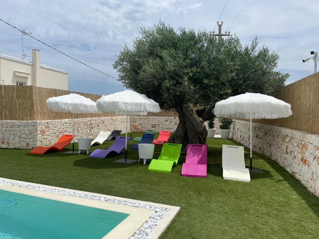 a group of chairs and umbrellas next to a pool at Tuo Hotel in Polignano a Mare