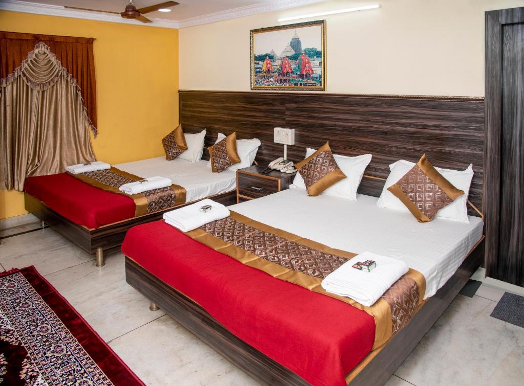 Habitación de hotel con 2 camas con sábanas rojas en Vrindavan Comfort Inn, en Ameerpet